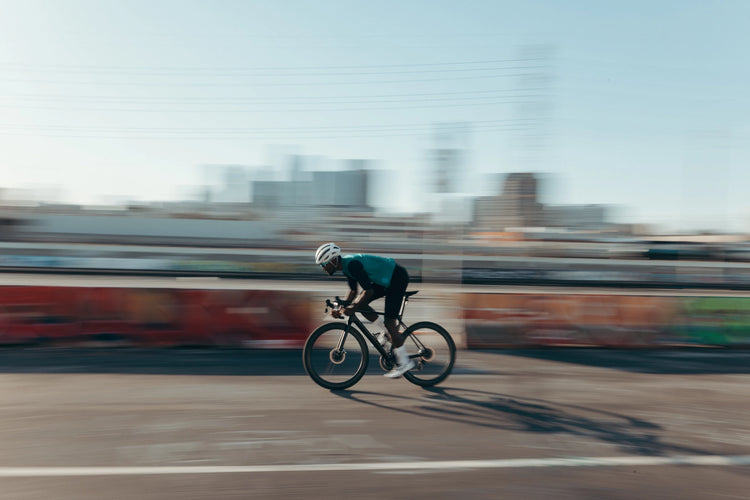 mand cykler hurtigt på en vej med 100% cykelbriller