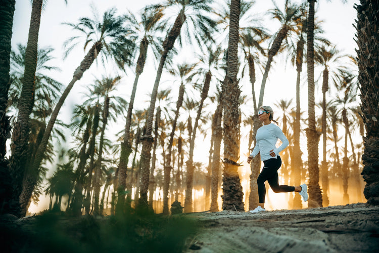 kvinde løber mellem palmer med 100% solbriller på